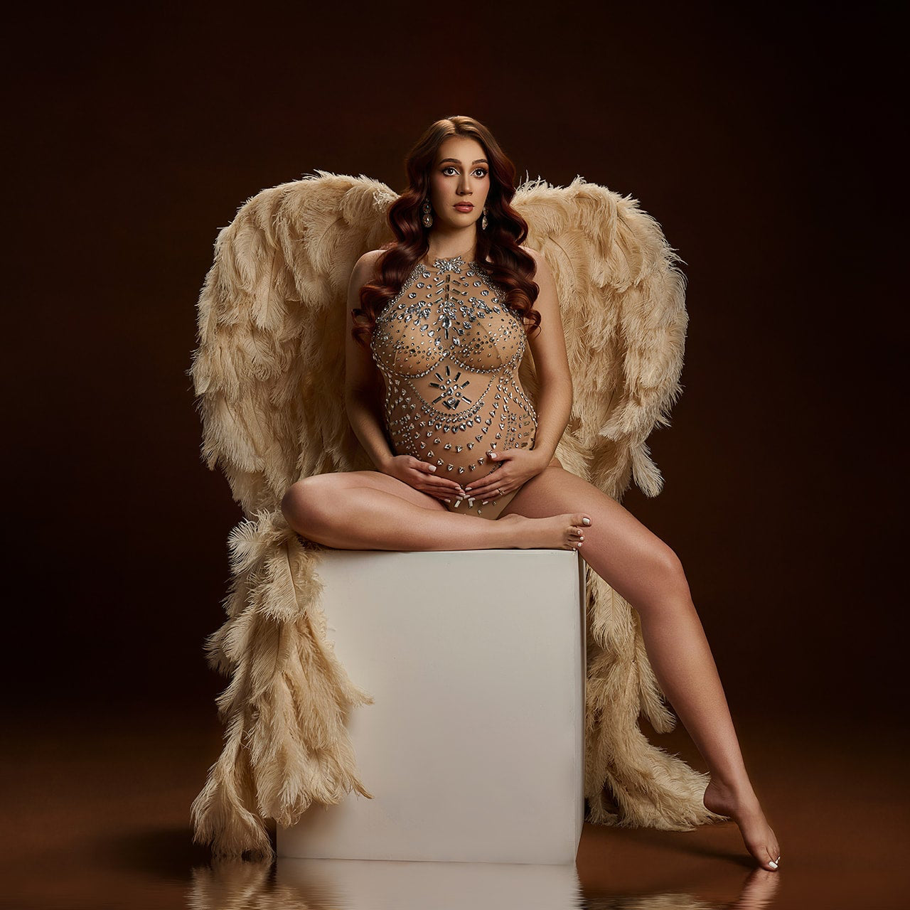 Model with angel wings sitting on a white block against a dark background Houston